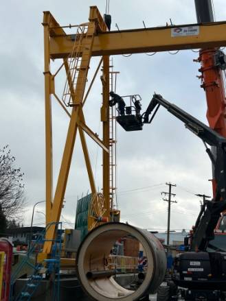 modern crane equipment, innovative, rotating its arm, photorealistic, surrounded by skyscrapers, highly detailed, workers securing loads below, fine textures, bright yellows and reds, midday sunlight, shot with a 50mm lens.