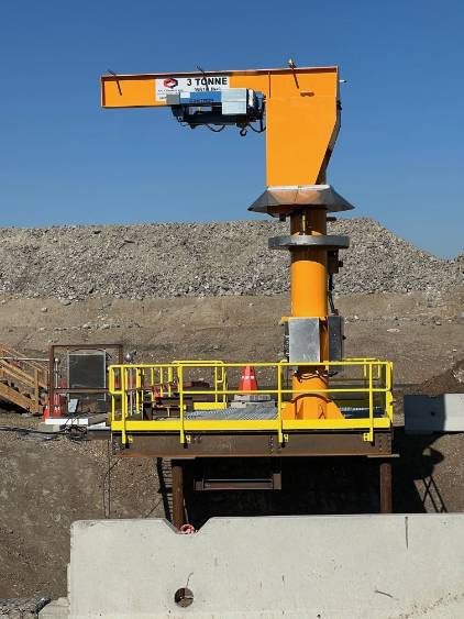 modern crane equipment, innovative, rotating its arm, photorealistic, surrounded by skyscrapers, highly detailed, workers securing loads below, fine textures, bright yellows and reds, midday sunlight, shot with a 50mm lens.