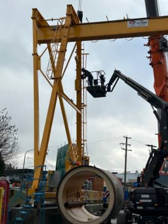 modern crane equipment, innovative, rotating its arm, photorealistic, surrounded by skyscrapers, highly detailed, workers securing loads below, fine textures, bright yellows and reds, midday sunlight, shot with a 50mm lens.
