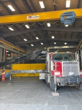 modern crane equipment, innovative, rotating its arm, photorealistic, surrounded by skyscrapers, highly detailed, workers securing loads below, fine textures, bright yellows and reds, midday sunlight, shot with a 50mm lens.